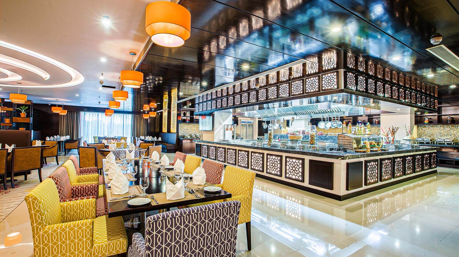 Restaurant booths and patterned chairs beneath curved ceiling lights